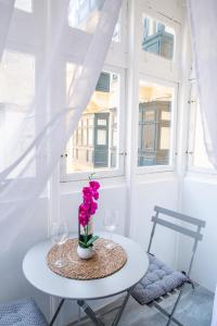 a table with two glasses and a vase with flowers on it at Valletta Waterfront 2 Beds Flat in Il-Furjana