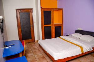 a bedroom with a bed and a blue table and doors at SUP HOTEL in Douala