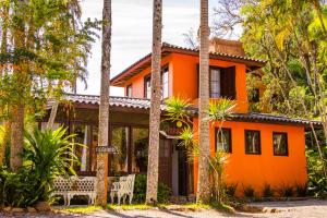 een oranje huis met palmbomen ervoor bij Pousada Paradise Ferrugem in Garopaba