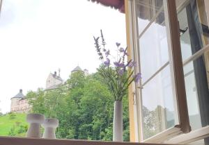 un vaso con fiori viola seduto sul davanzale di una finestra di ciao-aschau Haus zur Burg FeWo Bergfest Ap110 a Aschau
