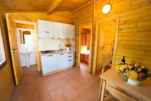 kuchnia z białymi szafkami i stołem w kabinie w obiekcie Camping dei Tigli w mieście Torre del Lago Puccini