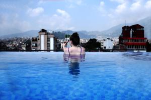a woman taking a picture of a city in a swimming pool at Divine Kathmandu Hotel in Kathmandu