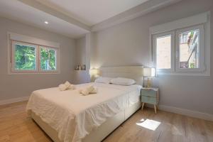 um quarto branco com uma cama e 2 janelas em Central Torremolinos Apartment em Torremolinos