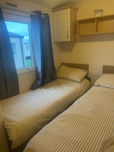 2 Betten in einem kleinen Zimmer mit Fenster in der Unterkunft 3 Bedroom Caravan - Maples 126, Trecco Bay in Newton