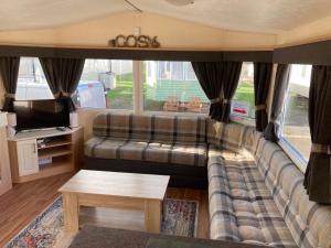 ein Wohnzimmer mit einem Sofa und einem TV in der Unterkunft 3 Bedroom Caravan - Maples 126, Trecco Bay in Newton