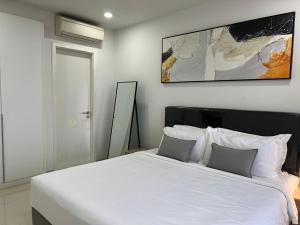 een slaapkamer met een groot wit bed met 2 kussens bij ImPian 1BR condo in Phnom Penh