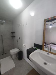 a bathroom with a sink and a toilet and a mirror at Vila da Praça Pousada in Capitólio