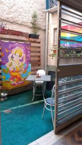 a patio with a table and a painting on the wall at Arco Iris Guest House in Porto Alegre