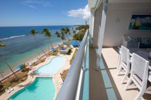 a balcony with a view of the ocean and a swimming pool at Las Olas Juan Dolio Beachfront View in Juan Dolio
