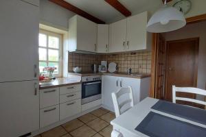 a kitchen with white cabinets and a table and chairs at Das Refugium in Worpswede