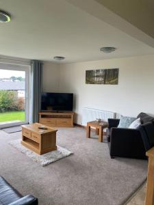 a living room with a couch and a tv and a table at Bungalow in Pillaton in Saltash