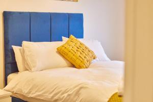 a bed with a blue headboard and white pillows at The Norham - Properties Unique in North Shields