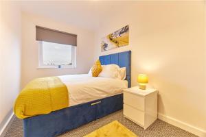 a bedroom with a blue bed and a window at The Norham - Properties Unique in North Shields