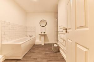 a white bathroom with a tub and a sink at The Norham - Properties Unique in North Shields