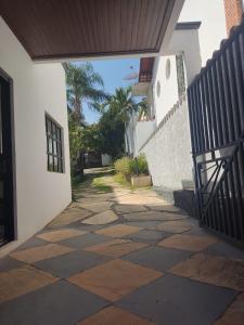 a walkway leading into a white building with a fence at Vila da Praça Pousada in Capitólio