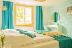 a bedroom with a bed with blue curtains and a window at Wellnessoase mitten in der Wasserfallstadt Triberg in Triberg