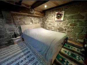 a bedroom with a bed in a stone wall at Cassiopée in Figeac