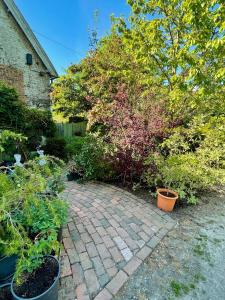 un jardin avec des plantes en pot et une passerelle en briques dans l'établissement The Grannery, à Wadhurst