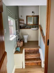 a bathroom with a sink and a toilet and stairs at The Grannery in Wadhurst