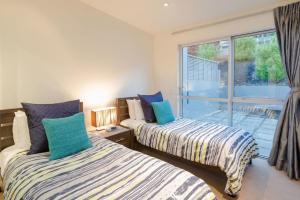 two beds in a room with a window at Lake View Villa, Great location and Amazing views in Queenstown