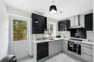 eine Küche mit schwarzen und weißen Geräten und einem Fenster in der Unterkunft Exquisite London Home - Parking - Sleeps 10 in Dagenham