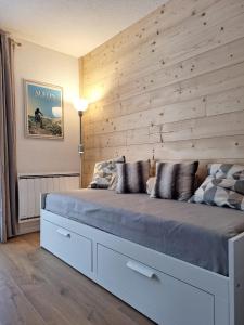 a bedroom with a large bed with a wooden wall at Studio Les 3 Lys Auron in Auron