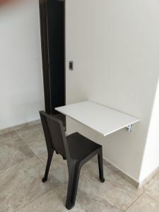 ein weißer Schreibtisch und ein Stuhl neben einer Wand in der Unterkunft Roshan in Cali + 8 Fotos