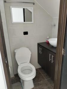 ein Badezimmer mit weißer Toilette und Waschbecken in der Unterkunft Roshan in Cali
