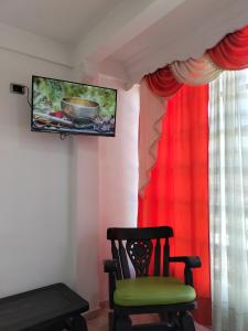 Ein Stuhl steht vor einem Fenster mit einem Fernseher. in der Unterkunft Roshan in Cali