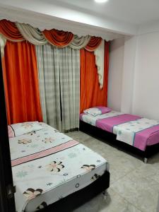 zwei Einzelbetten in einem Zimmer mit Vorhängen in der Unterkunft Roshan in Cali
