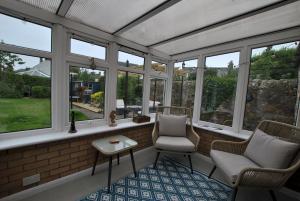 a screened in porch with two chairs and a table at Carpenters Cottage- coastal stay with garden in Pittenweem