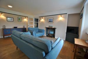 a living room with a couch and two chairs and a fireplace at Carpenters Cottage- coastal stay with garden in Pittenweem