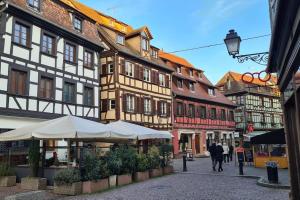 uma rua com edifícios e guarda-sóis numa cidade em Duplex Centre - Le Marché em Obernai