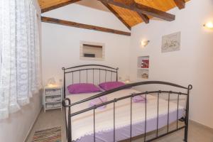 a bedroom with a metal bed with purple pillows at Stone houses Nikola in Podorljak +37 photos