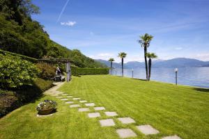 a grassy yard with a pathway next to the water at Yachting Residence in Ghiffa