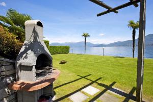 a pizza oven sitting on top of a lawn next to the water at Yachting Residence in Ghiffa