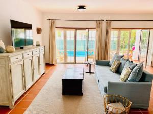 sala de estar con sofá azul y TV en Villa in Praia D'el Rey, Beach & Golf Resort en Praia del Rei