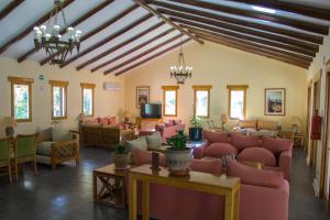 una sala de espera con sillas rosas, mesas y ventanas en Cabañas La Huayca - Caja Los Andes, en Pica