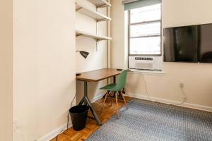 Cette chambre comprend un bureau, une télévision et une chaise. dans l'établissement ✪ Large 2 Bedrooms ✪ Queen Beds ✪ Work Stations, à New York