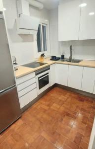 a kitchen with white cabinets and a wooden floor at La puerta al Mar in Calafell