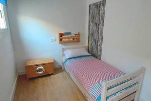 a small bedroom with a bed and a wooden headboard at La puerta al Mar in Calafell