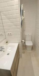 a white bathroom with a sink and a toilet at La puerta al Mar in Calafell +3 photos