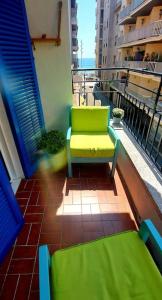 a balcony with a green chair on a building at La puerta al Mar in Calafell
