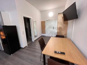 Habitación con mesa de madera y TV en la pared. en 24seven Apartments - Self Check-IN, en Landshut