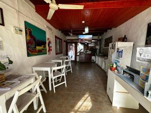 a restaurant with tables and chairs and a refrigerator at Posada Costa del Sol in Colón +26 photos