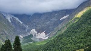 a view of a mountain valley with trees and clouds at Gaul Gavkhe Hotel in Ushguli