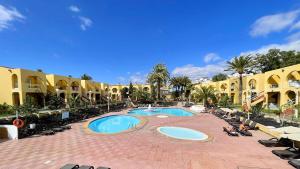 a resort with two pools and people sitting in chairs at Strahouse Stilish House in Maspalomas