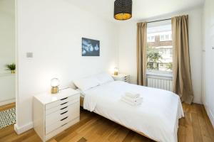 biała sypialnia z białym łóżkiem i oknem w obiekcie 1 Bedroom Notting Hill w Londynie