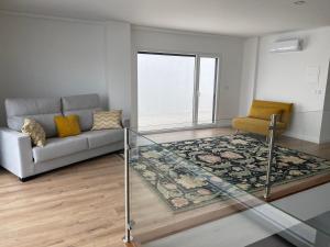 uma sala de estar com um sofá e uma mesa de vidro em Casa Roma em Sesimbra