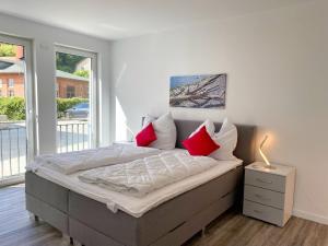 Schlafzimmer mit einem Bett mit roten und weißen Kissen in der Unterkunft Ferienappartement Balve in Sassnitz